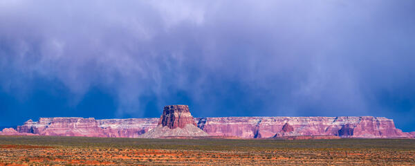 Arizona landscape scene of Sun shining on Red Rock buttes with storm clouds over the buttes at Lake Powell
