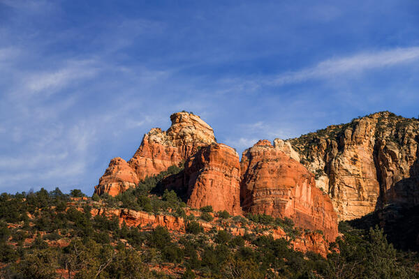 Sedona lanscape scene of three red rock formations being softly lit up by the setting sun
