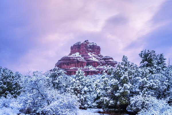 Sedona lanscape scene of the red rock formation known as Bell Rock covered in fresh snow along with the surrounding trees