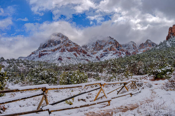 Sedona lanscape scene of a snow-covered fence line in front of snow-covered mountains