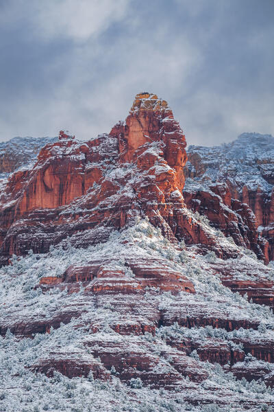 Sedona lanscape scene of a vertical view of layers of red rock and snow on a snow-covered formation
