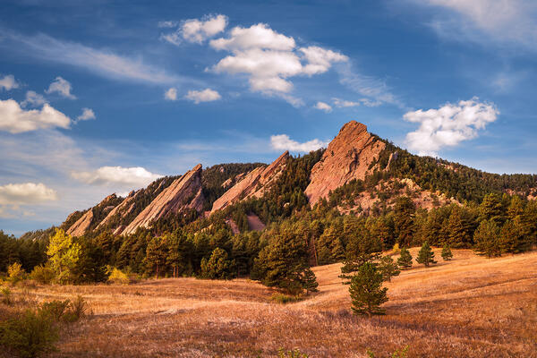 early warm light on a meadow with Fall color and on the mountains called The Flatirons in Colorado