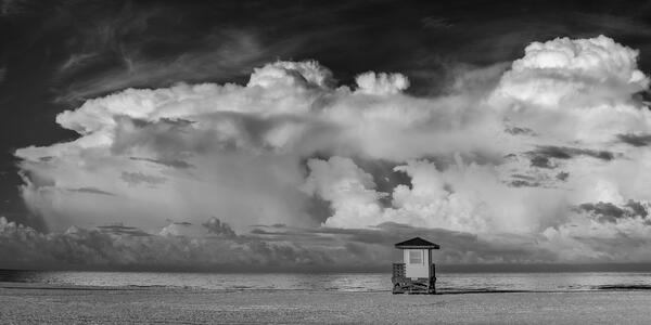 black and white landscape view of morning storm clouds with color off the beach and lifeguard stand at lido key florida