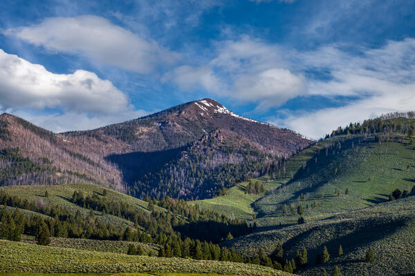 Idaho landscazpe scene of a view of a mountain sitting between two hills on a remote road in Idaho