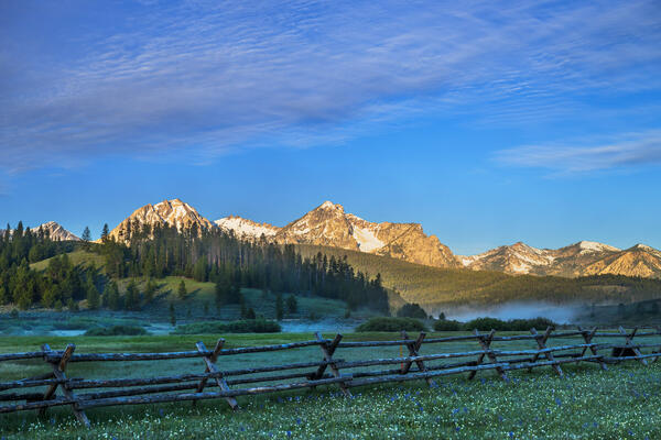 Idaho landscazpe scene of the Sawtooth Mountains behind an old split-rail fence near Stanley Idaho