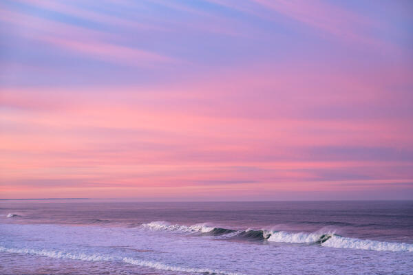 Oregon Coast landscape scene of sunrise sky with pastel colors over the ocean waves at Bandon Beach