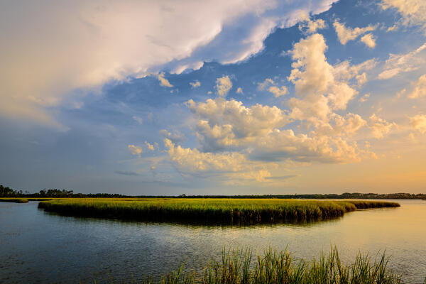 A curving river around a marsh with sig sunset clouds