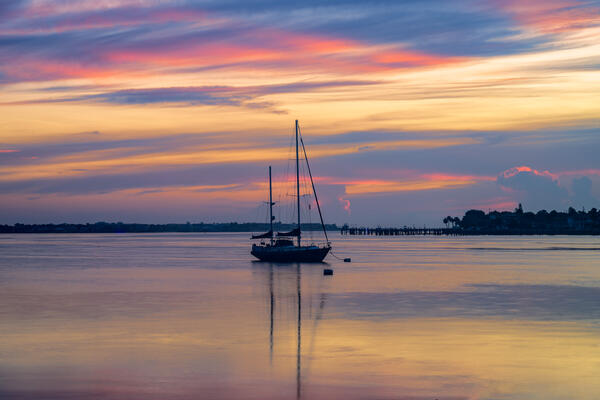 A sailboat in silhouette at sunrise in calm water in St. Augustine, Florida