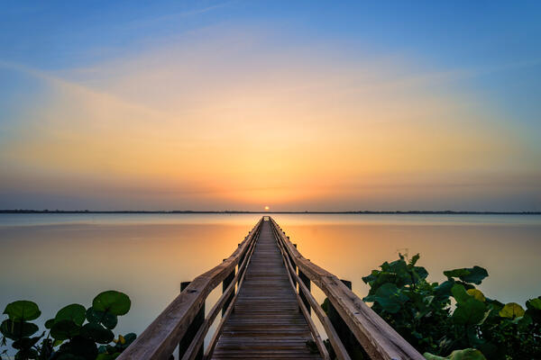 Sun just over the horizon lined up with a long dock in Jensen Beach Florida