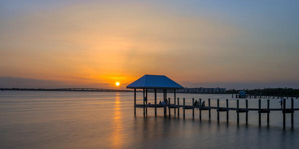 A small covered dock with sunset skies on a bay in Florida