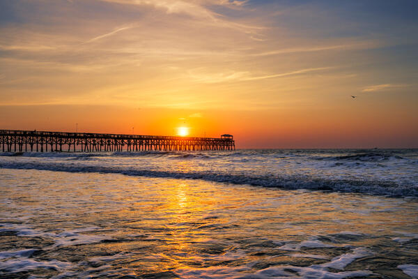 South Carolina landscape scene of a colorful sunrise on the beach above the pier in Myrtle Beach