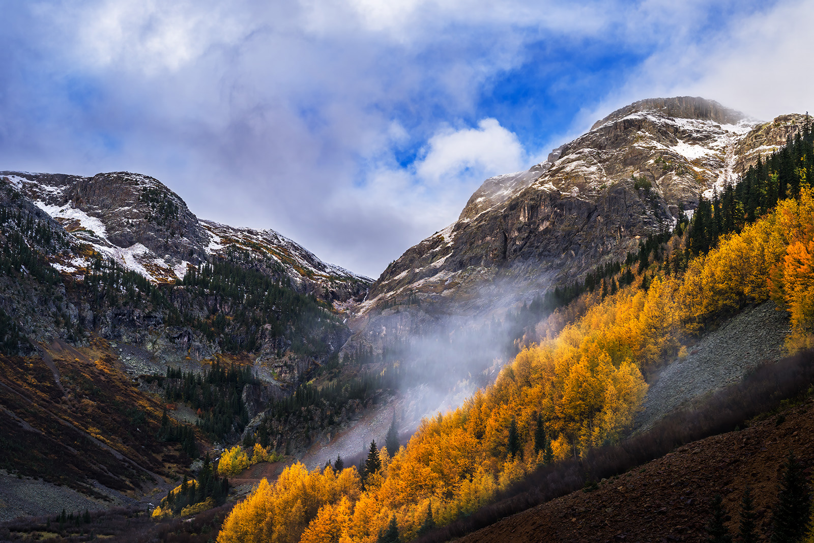 Turbulence landscape view of rugged mountains with stormy skies and deep orange fall color