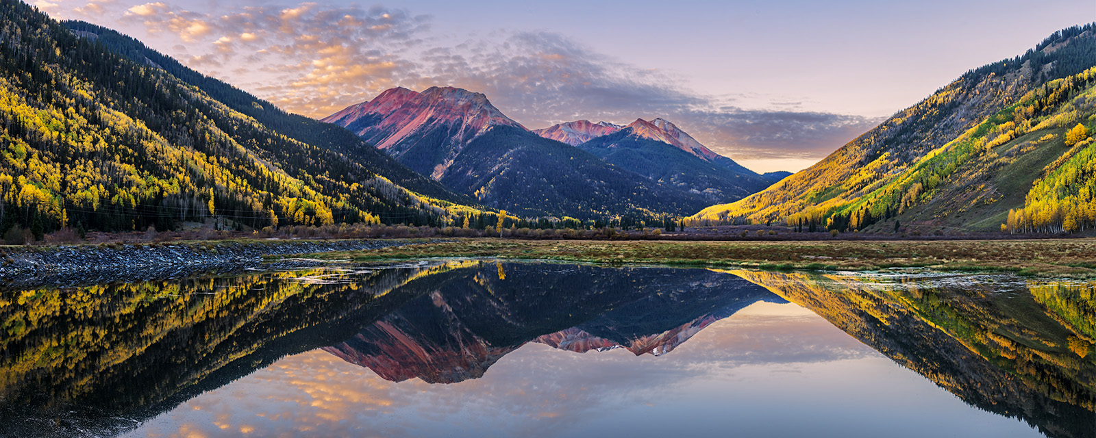 Crystal Clear Morning panoramic landscape view of colorado mountains and fall colors reflecting in crystal lale