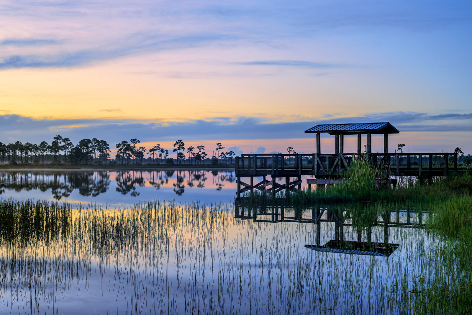 Quiet Moment A small dock reflecting in the calm water at a lake beforre sunrise